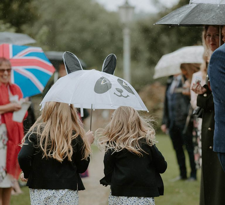 Children walk under umbrella at October wedding