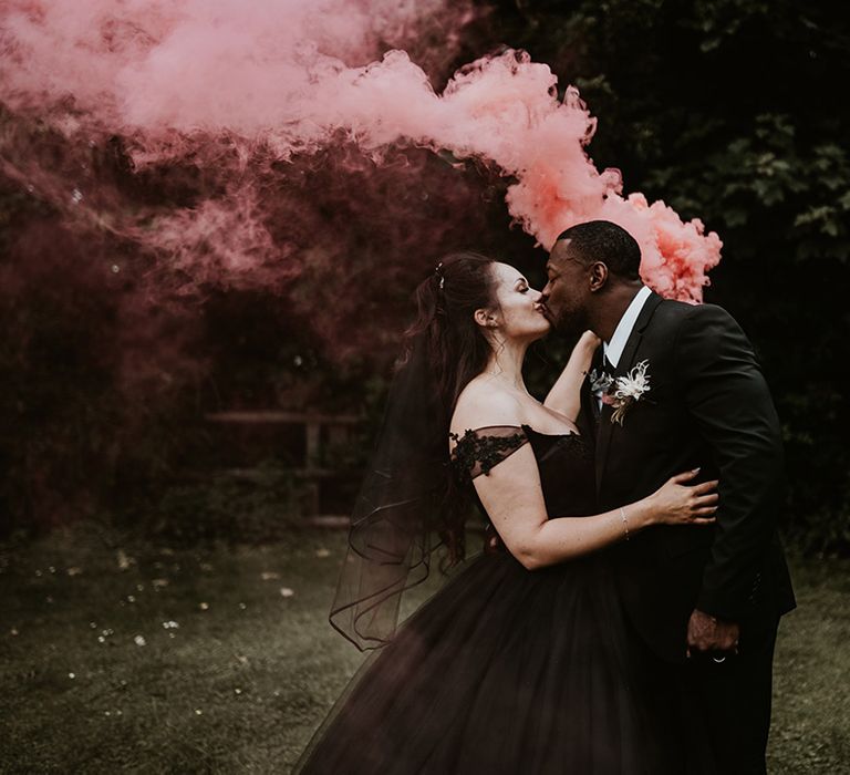 Bride & groom hold pink smoke bomb 