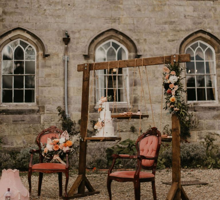 Chiddingstone Castle wedding inspiration with wooden frame cake display stand and orange velvet chairs with a bouquet resting on the seat