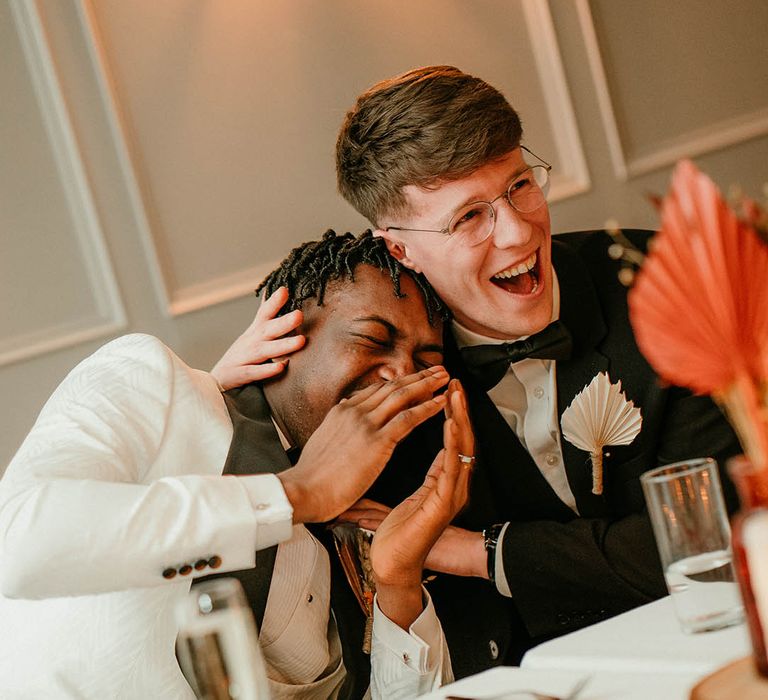 Groom laughs with a wedding guest