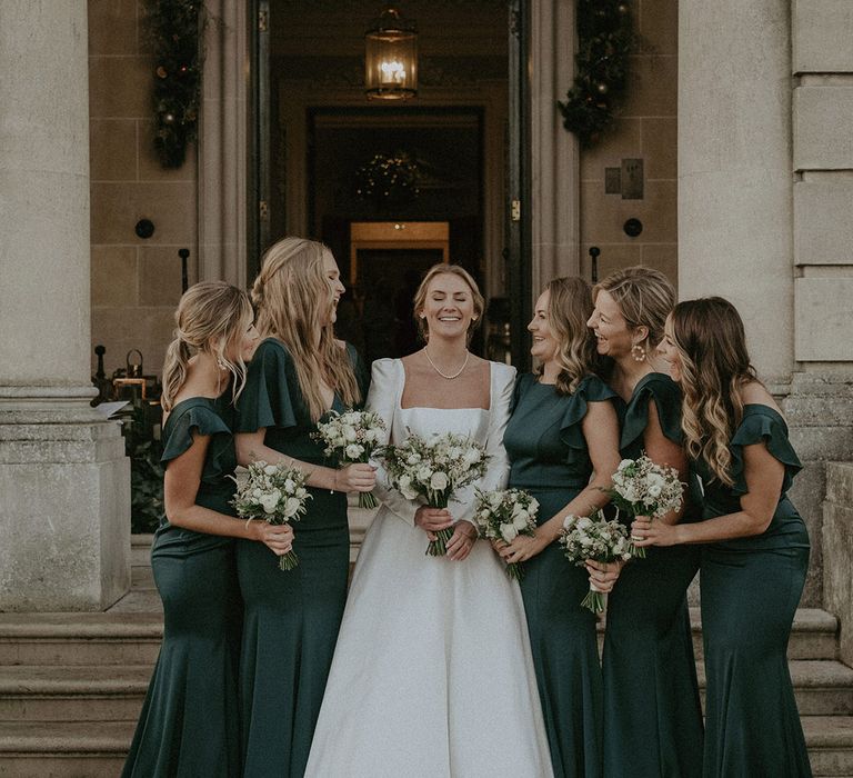 Bridal squad wearing Suzanne Neville, long white wedding dress and long bottle green dresses with black fur cropped coats