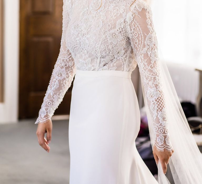 Bride in lace top long sleeve fitted wedding dress with updo and veil and smoky eye makeup