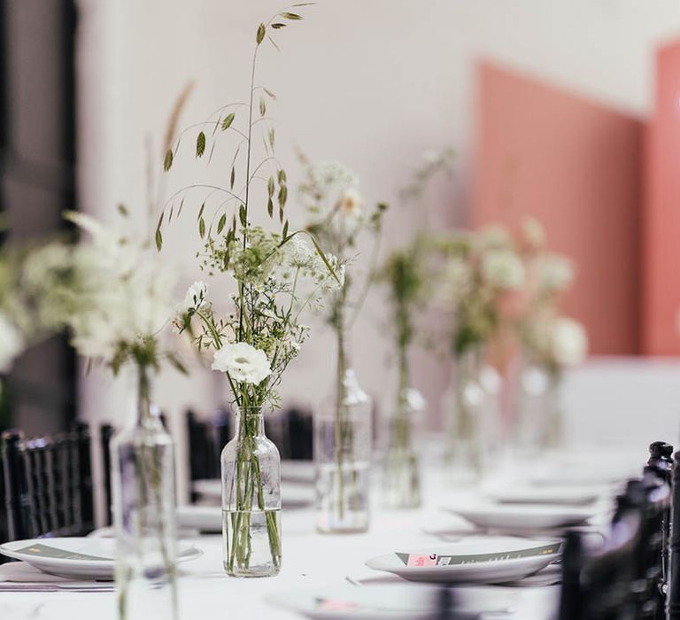 Small glass bottle vases of mini white flower arrangement