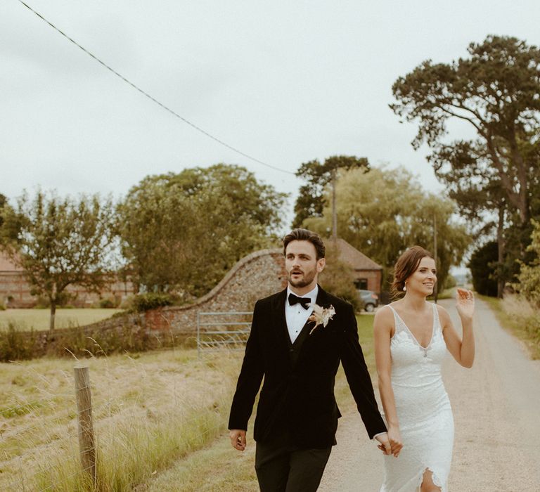 Bride and groom have their couple portraits as they walk holding hands around their wedding venue, Godwick Barn