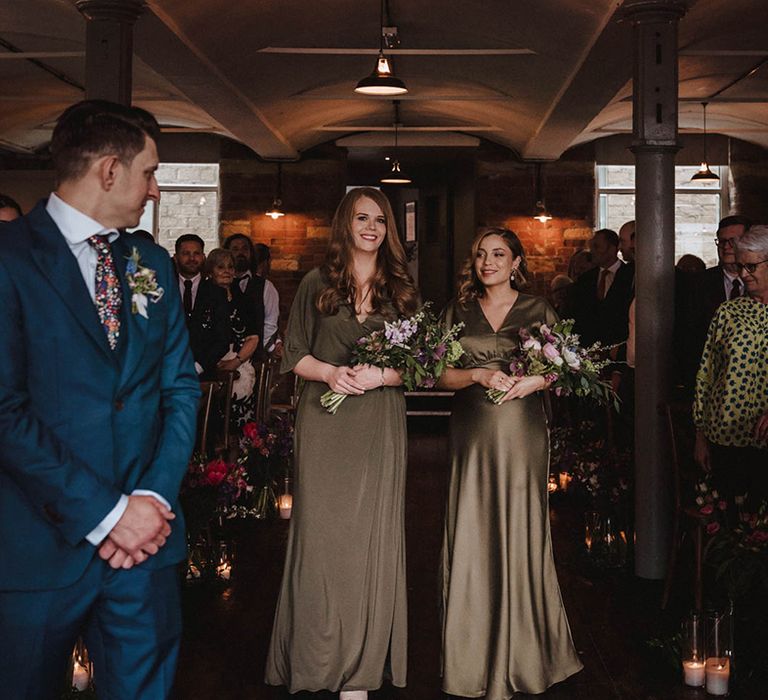 Bridesmaids in olive green coloured dresses holding spring bouquets for industrial wedding