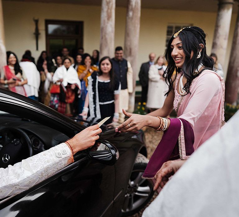 Wedding guest in traditional Indian wedding attire takes card from the groom