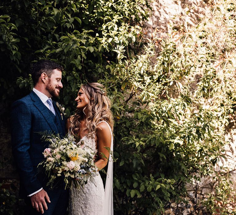 Bride and groom smile at each other for couple portraits 