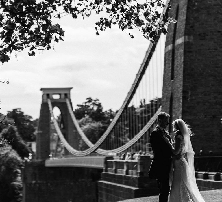 Bride and groom share an intimate embrace as they stand overlooking the Clifton suspension bridge in Bristol 