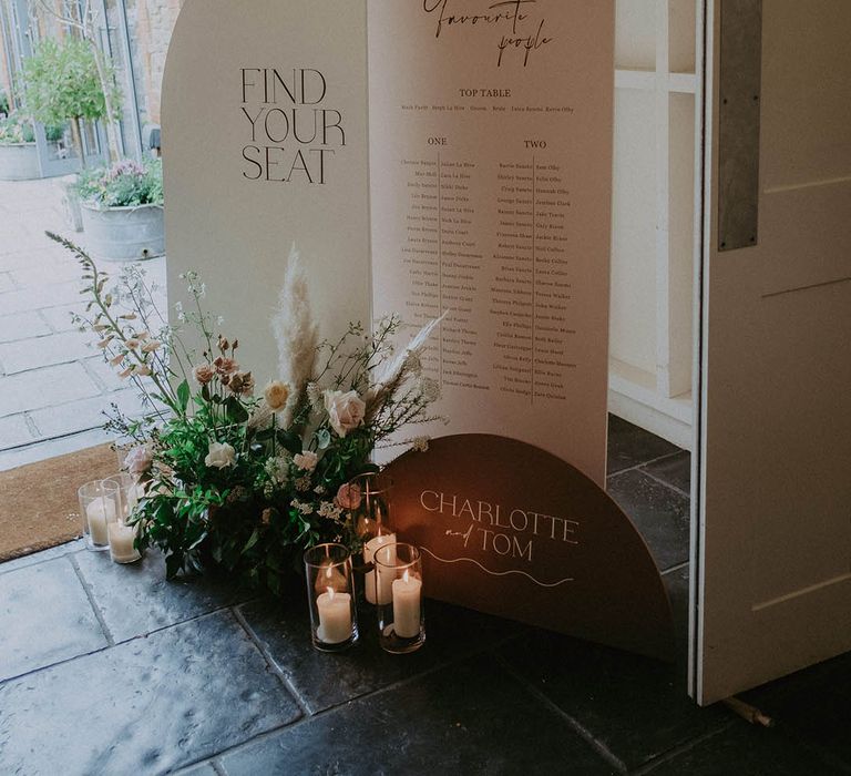 Wedding table plan and seating chart sign with roses, dried grass and candles 