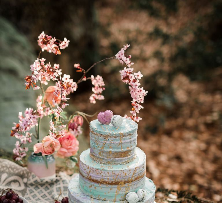 Three tier blue and purple iced wedding cake with mini purple and blue macarons 