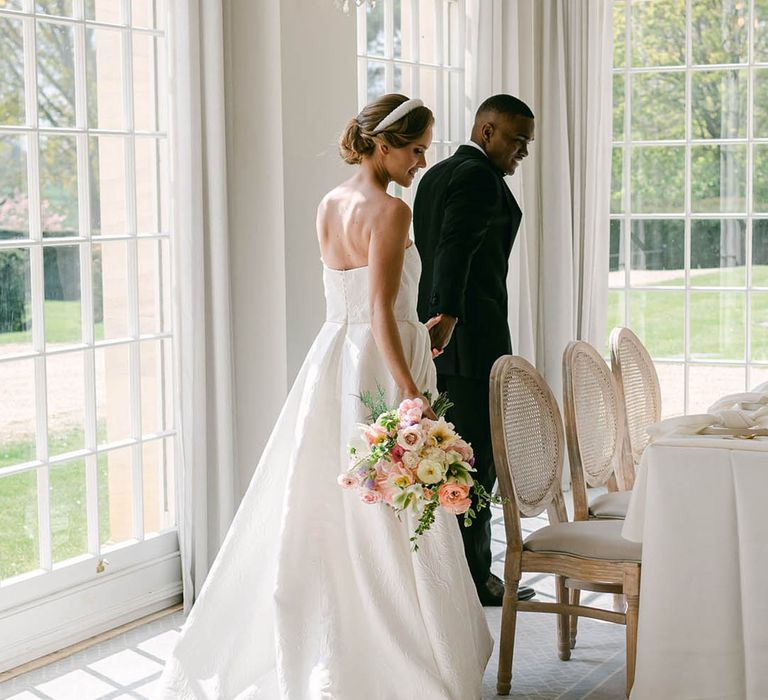 Bride and groom walk into Rushton Hall to take their seats together 