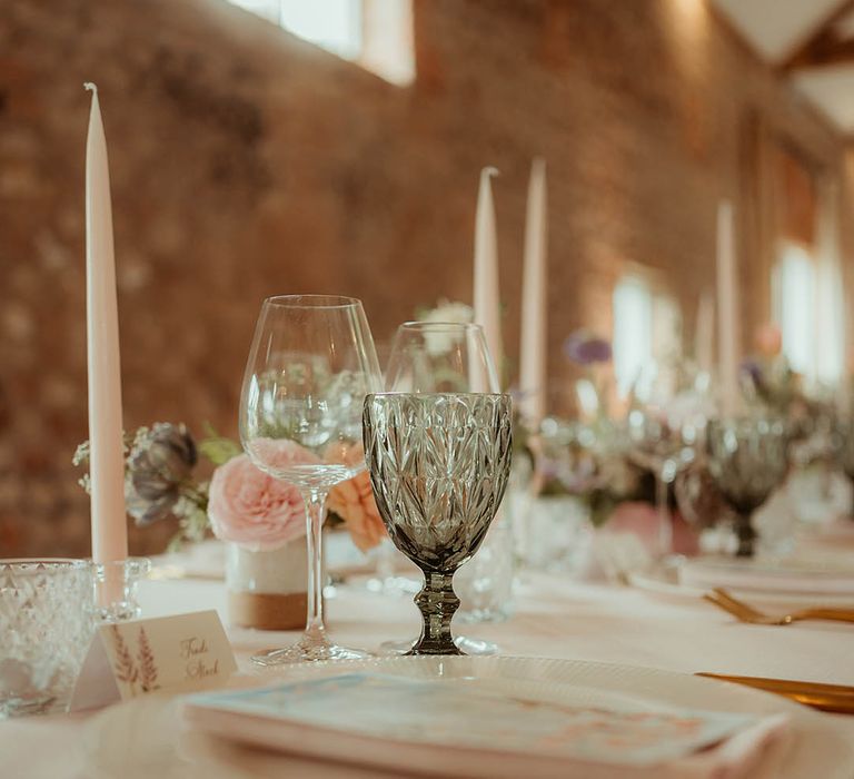 Pale pink taper candles with green glassware and pink and green flowers for the table settings 