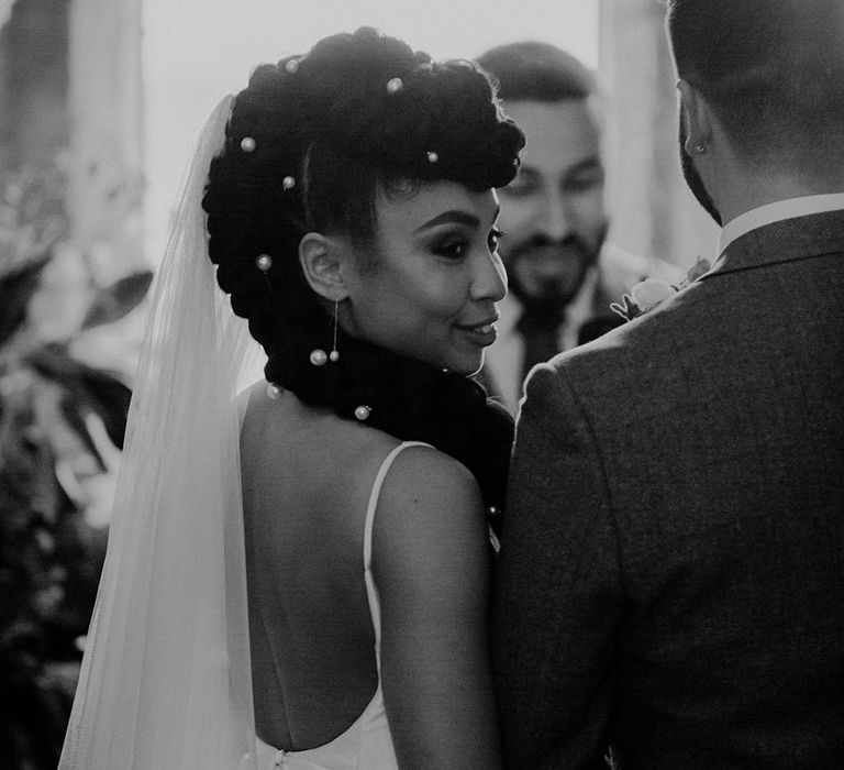 Bride wears floor length veil in her braided hair complete with pearl hair accessories 