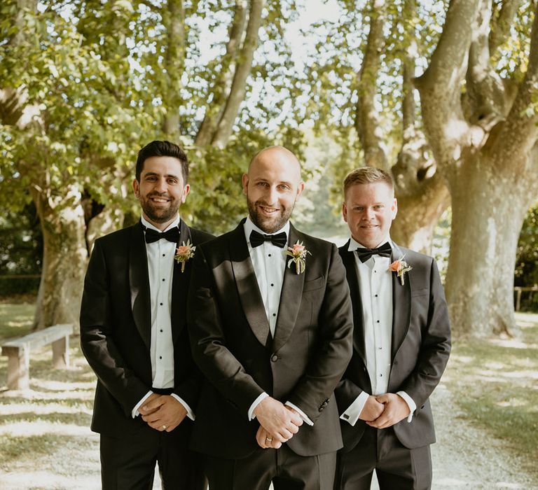 Groom and his groomsmen wearing black tie and pale pink floral buttonholes 