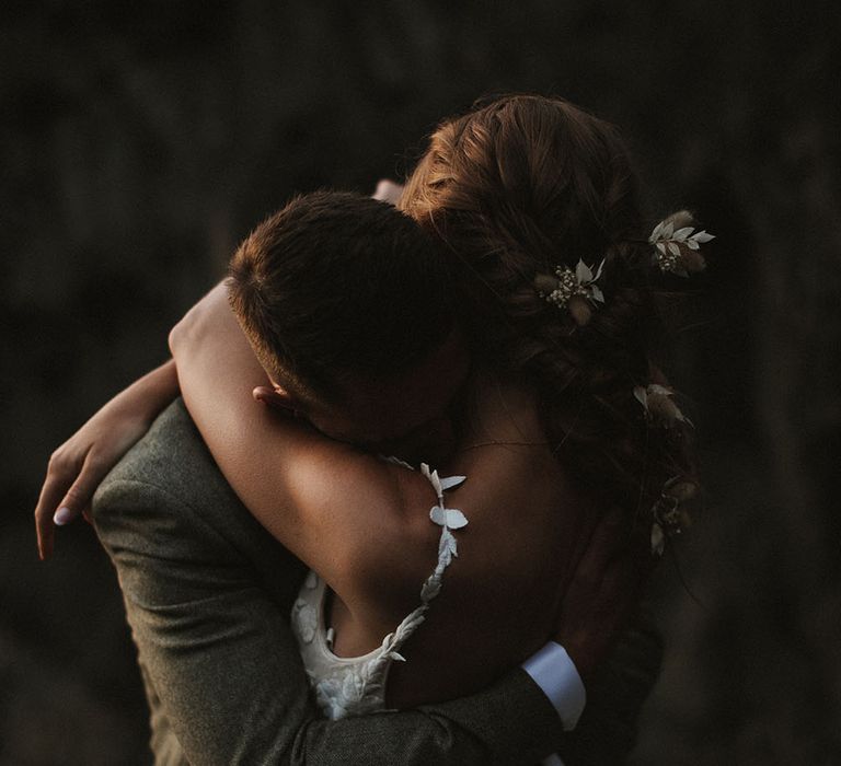 Bride wears floral embellished wedding dress and holds her groom in intimate image on their wedding day