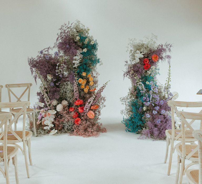 Bright and colourful flower columns decorating the aisle with coloured gypsophila, anthuriums, orchids, roses and more 