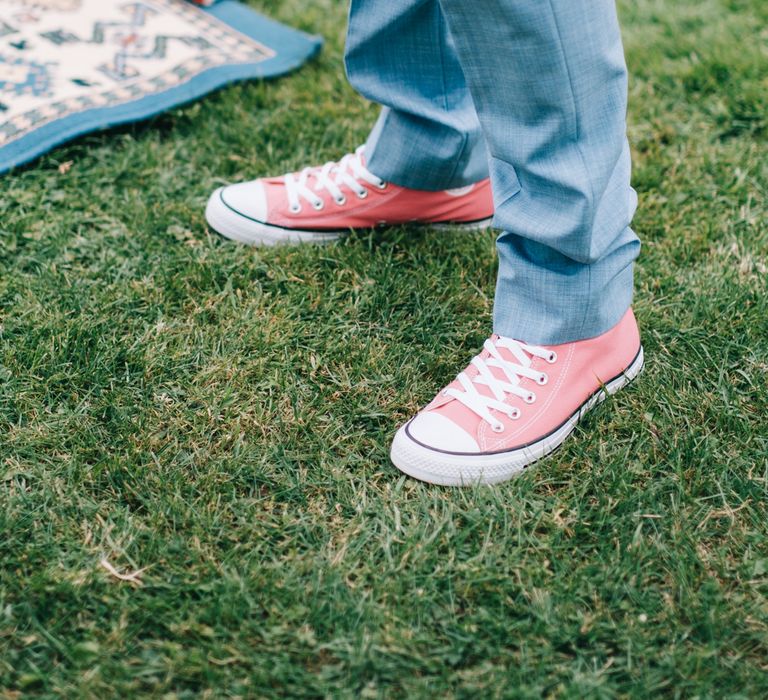 Groom wears dusty blue trousers and pink Converse trainers