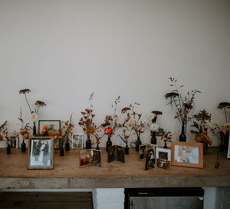 Small floral arrangements in brown medicine bottles beside personal photos 