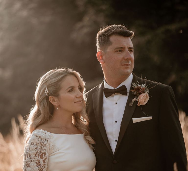 Groom in black tie and bride smiling during golden hour for couple portrait 