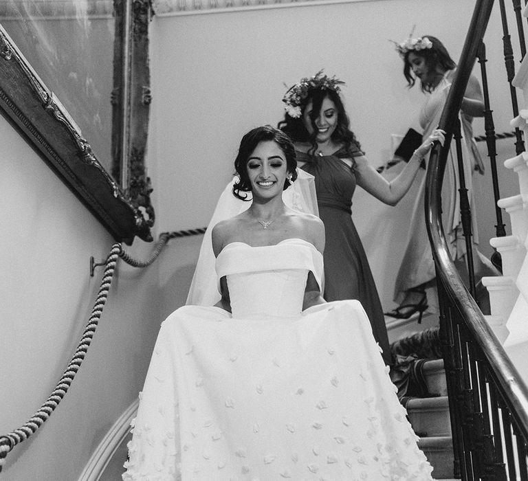 Bride walks down the stairs in bespoke Emma Beaumont design wedding dress with off-the-shoulder styling 