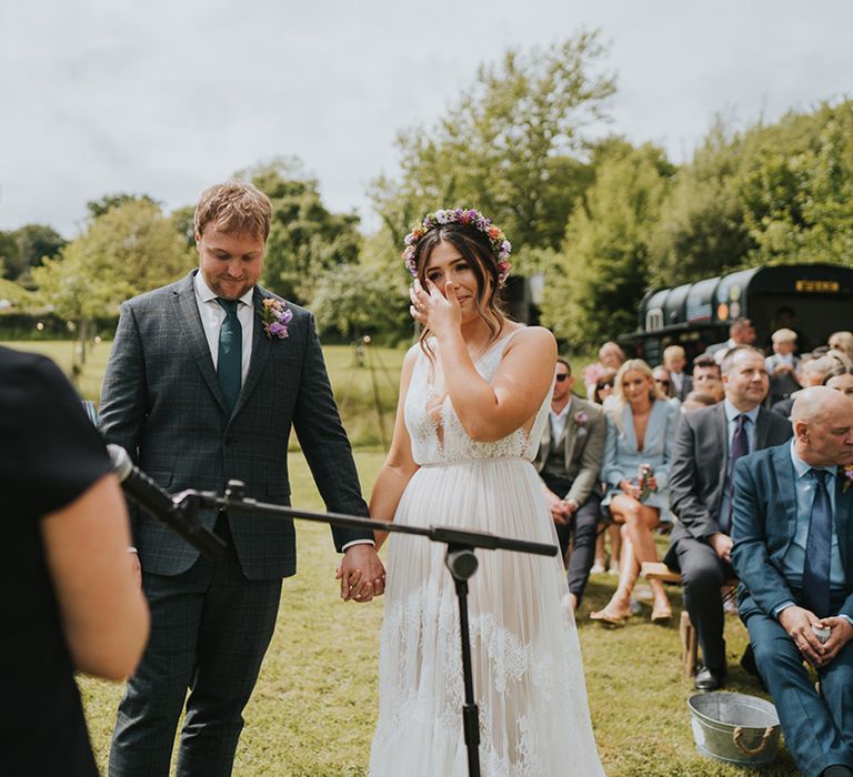 Bride wears boho styled scallop lace wedding dress with colourful floral crown