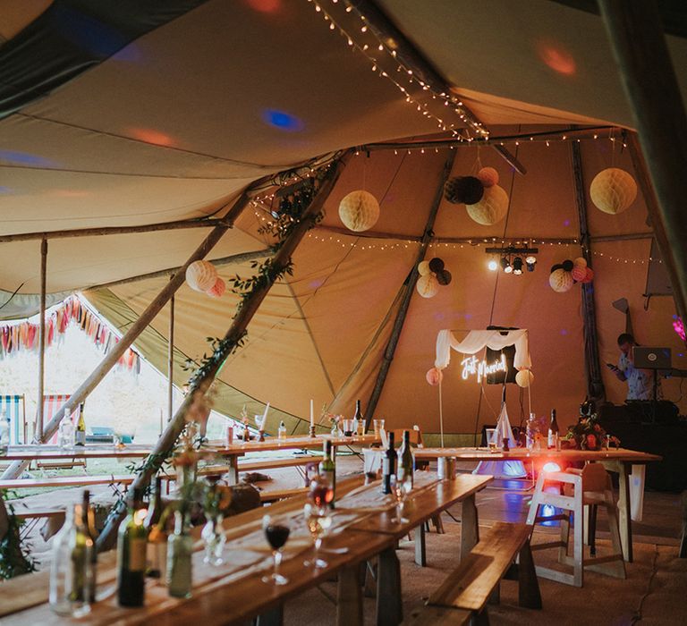 DIY tent wedding complete with neon signage, colourful bunting and wooden banquet tables 