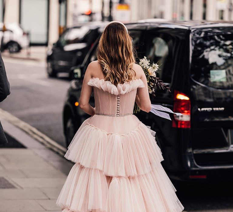 Bride wears blue pink wedding dress with fitted bodice complete with sheer fabric to the top and ruffled skirt 