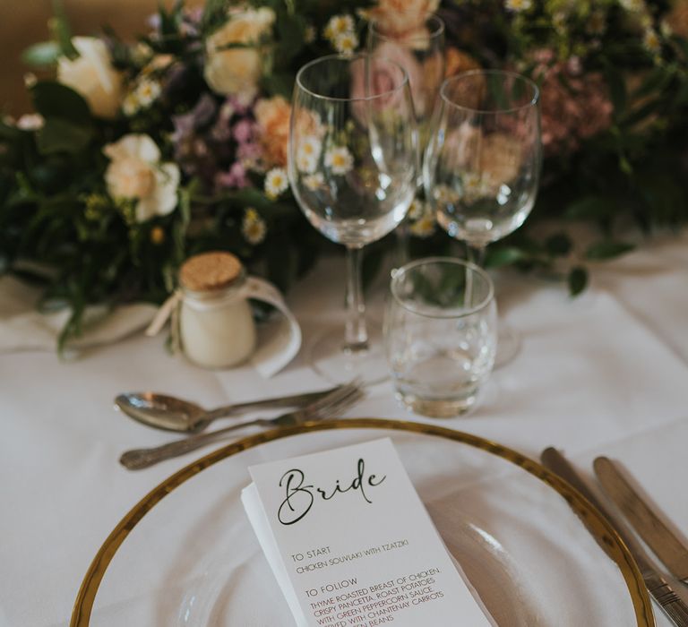 Black and white wedding menu stationery on clear charger plates with gold rim for classic and neutral wedding tablescape 