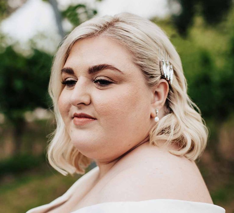 Bride in satin off the shoulder wedding dress, pearl drop wedding earrings and silver bridal hair accessories 