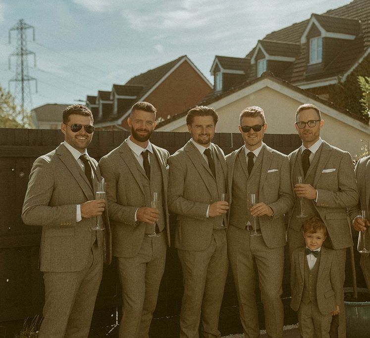 Groom and groomsmen in three piece grey suits for boho wedding 