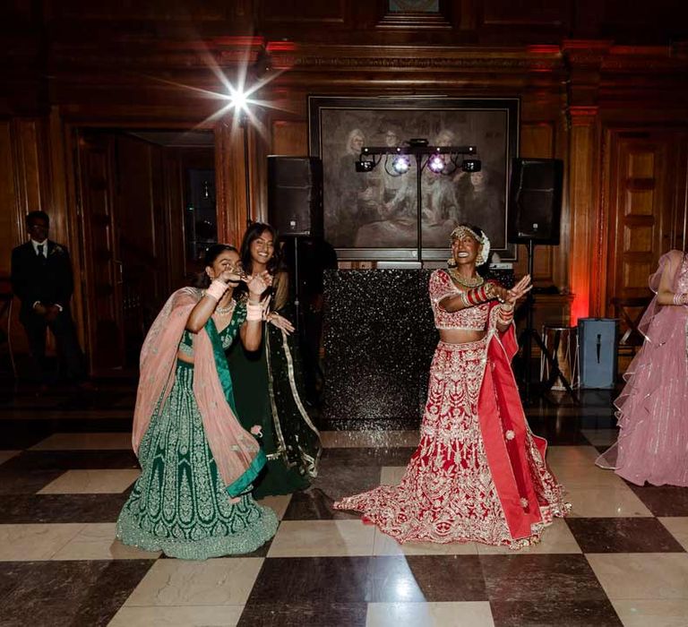 Bride in  red and gold bridal lehenga and gold, red, white gold and green bridal jewellery doing wedding dance at Inner Temple Hall 