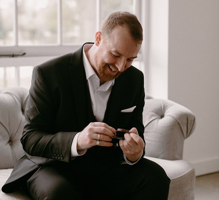 Groom sits to put on his new wedding watch present 