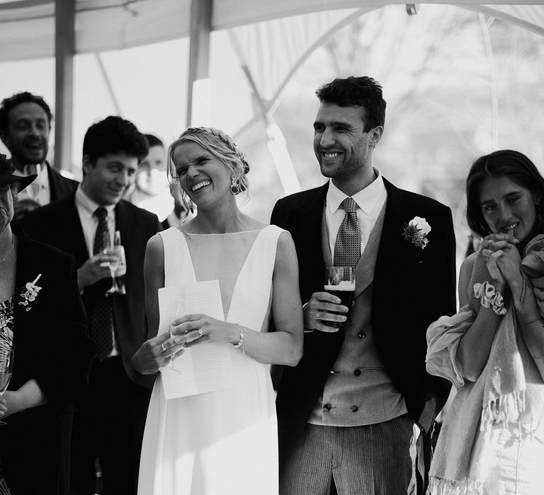 The bride and groom smile happily as they listen to the wedding speeches 