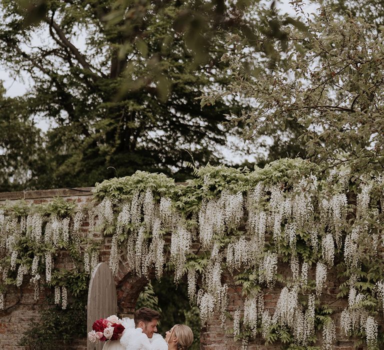 Bride in low back wedding dress kissing groom for cute wedding photo 