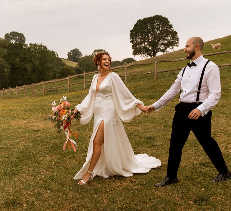 Bride walking in classic and traditional satin wedding dress with groom in black bow tie 