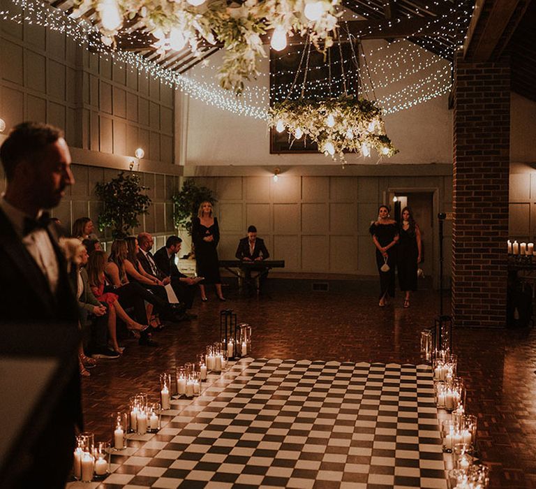 Larkspur Lodge wedding with checkerboard aisle lined with candle lanterns with fairy lights overhead 