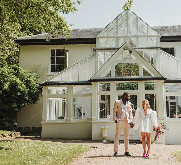 The bride and groom stand outside of the greenhouse at Polstrong Manor in Cornwall 