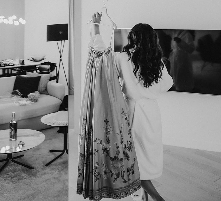 Bride in white dressing gown holds up traditional South Asian skirt while getting ready