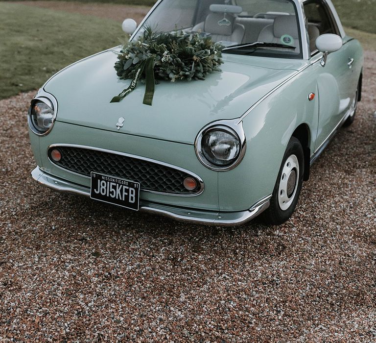 1991 green Nissan Figaro wedding car decorated with a green foliage Christmas wreath 