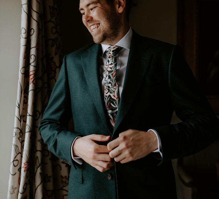 Groom in dark green suit with a jungle leaf tie from Peggy and Finn