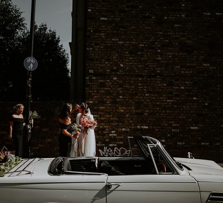 Bridal party walk to the wedding car together with black bridesmaid dresses 