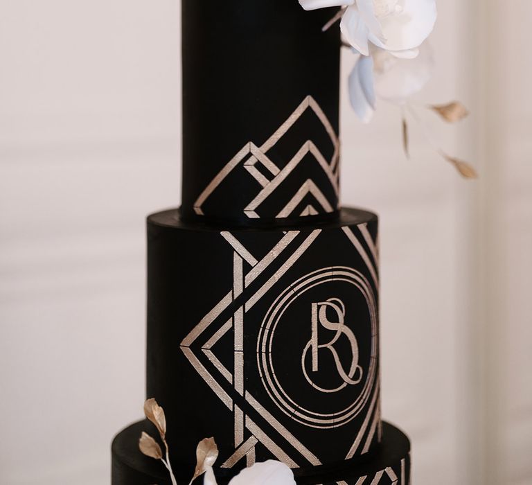 White roses act as cake topper on black and gold art deco wedding cake 