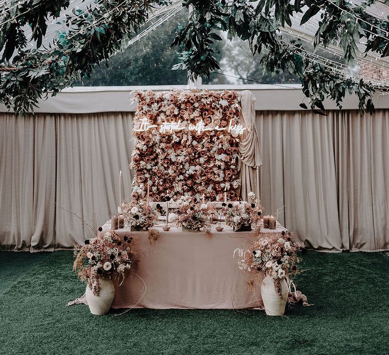 The Holford Estate marquee wedding with pink flower wall and neon sign as the backdrop to the romantic sweetheart table 