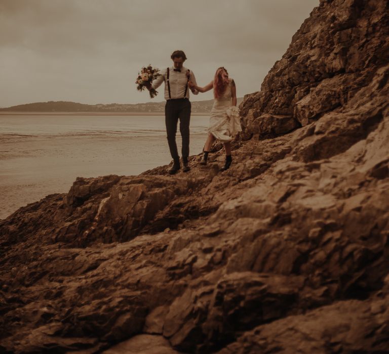 Bride and groom walking on the rocks at beachside elopement