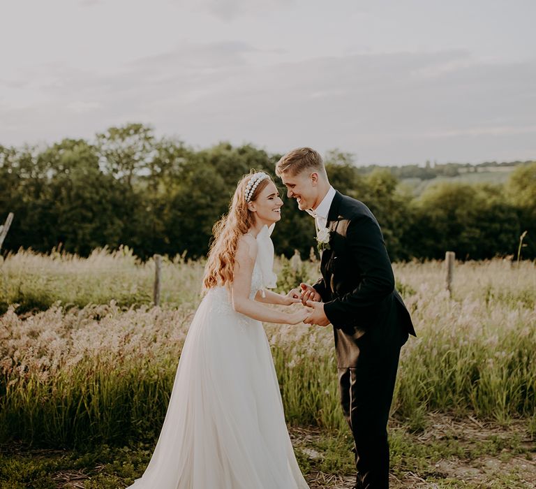 Bride and groom laughing in a field 