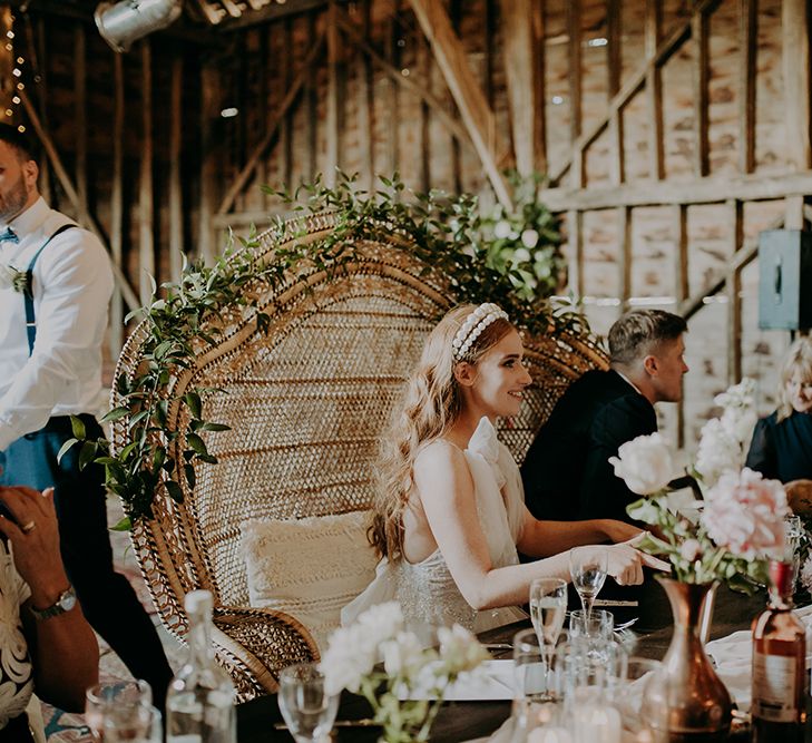 Bride in pearl headdress sitting in a peacock chair 