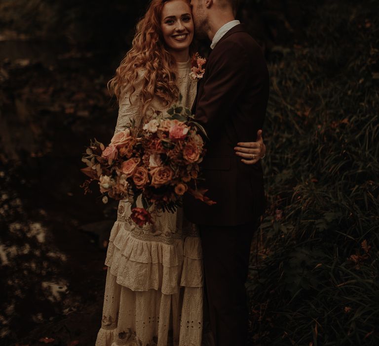 Bride with long wavy hair holding an autumn wedding bouquet 