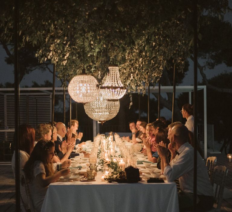 Intimate outdoor wedding reception with chandelier light installation