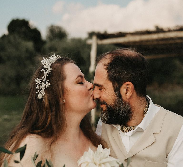 Bride kisses Groom's forehead with olive bouquet