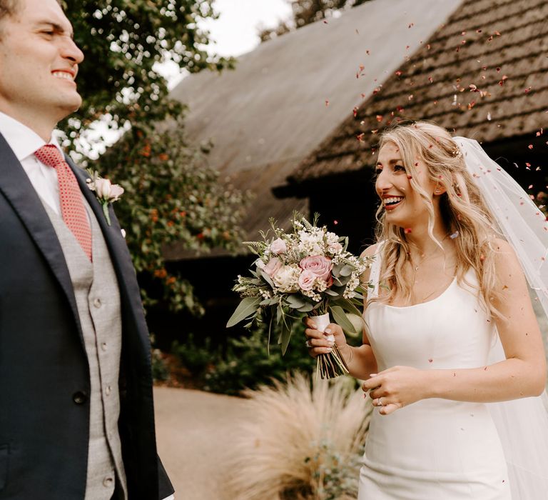 Bride in Suzanne Neville Coco wedding dress being showered with confetti 